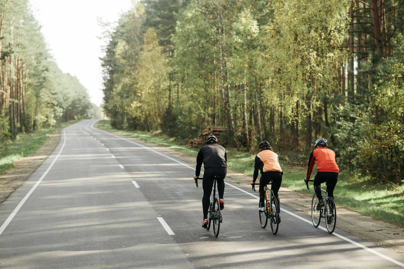 Drei Rennradfahrer in der Natur auf der Straße