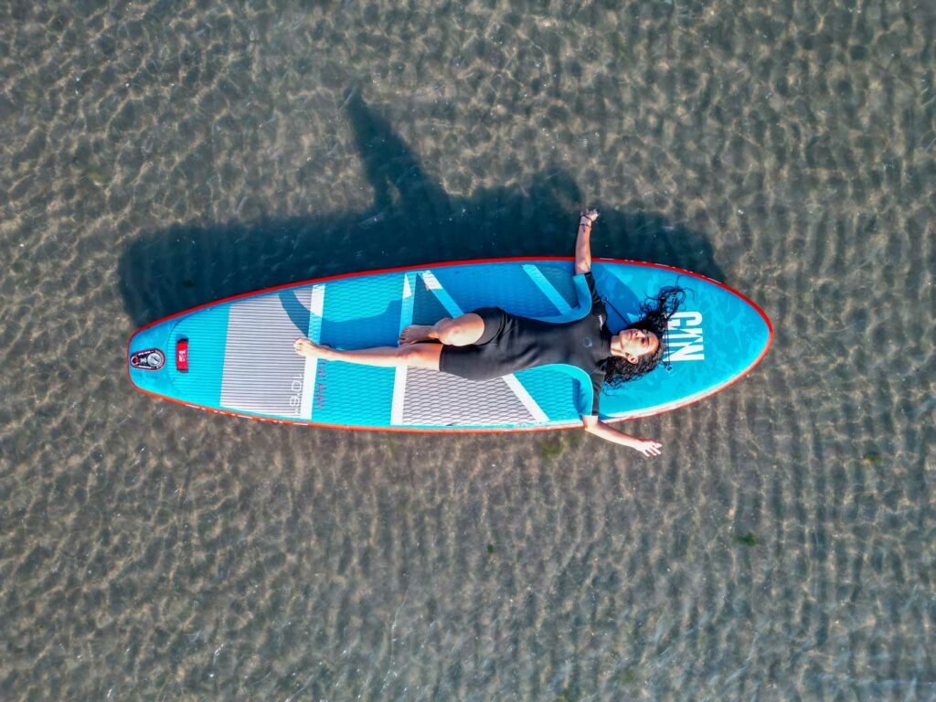 Frau liegt auf einem Stand Up Paddle auf dem See