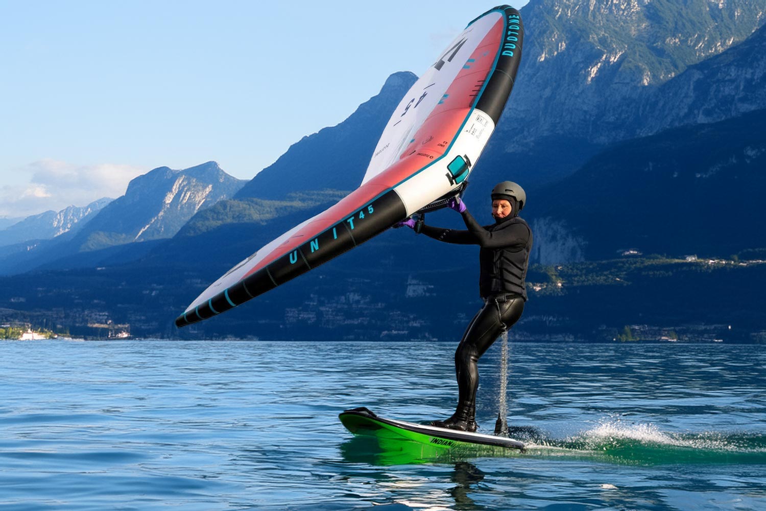Frau surft auf einem Board mit einem Wing über den Gardasee