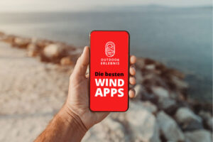 Mann hält sein Handy vor einem See hoch