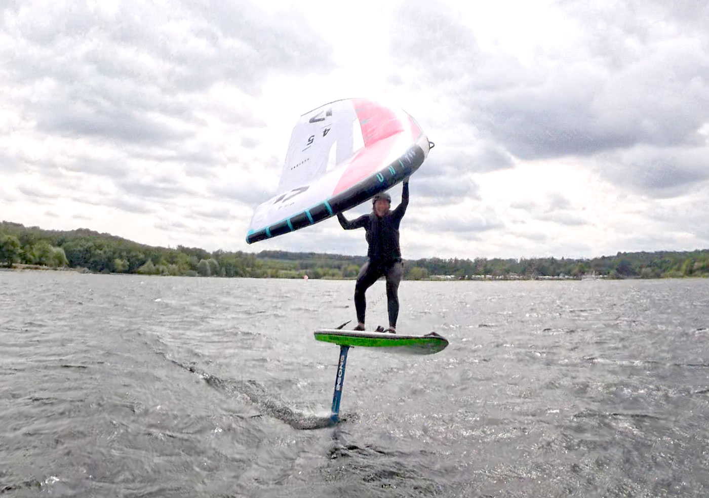 Frau ist am Wingfoilen auf einem See und läuft Höhe
