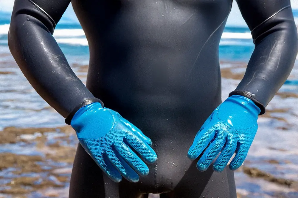 Mann trägt Putzhandschuhe beim Wingfoilen als Layering Lösung