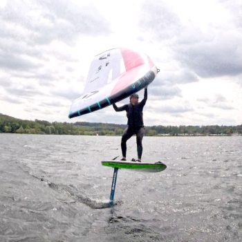 Frau ist am Wingfoilen auf einem See und läuft Höhe
