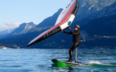 Frau surft auf einem Board mit einem Wing über den Gardasee