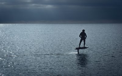 man in black wet suit standing on brown wooden paddle board during daytime